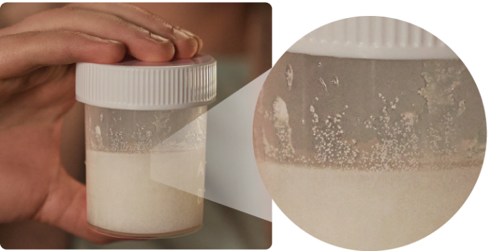 A photograph of a hand holding a lidded jar of LUMRYZ mixture, including a close-up view of the gritty texture.