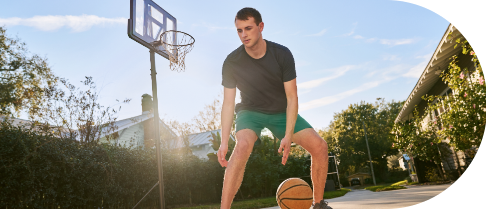 A young man playing basketball in a driveway.